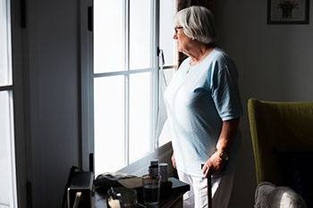 TEACH - Senior women looking out her living room window